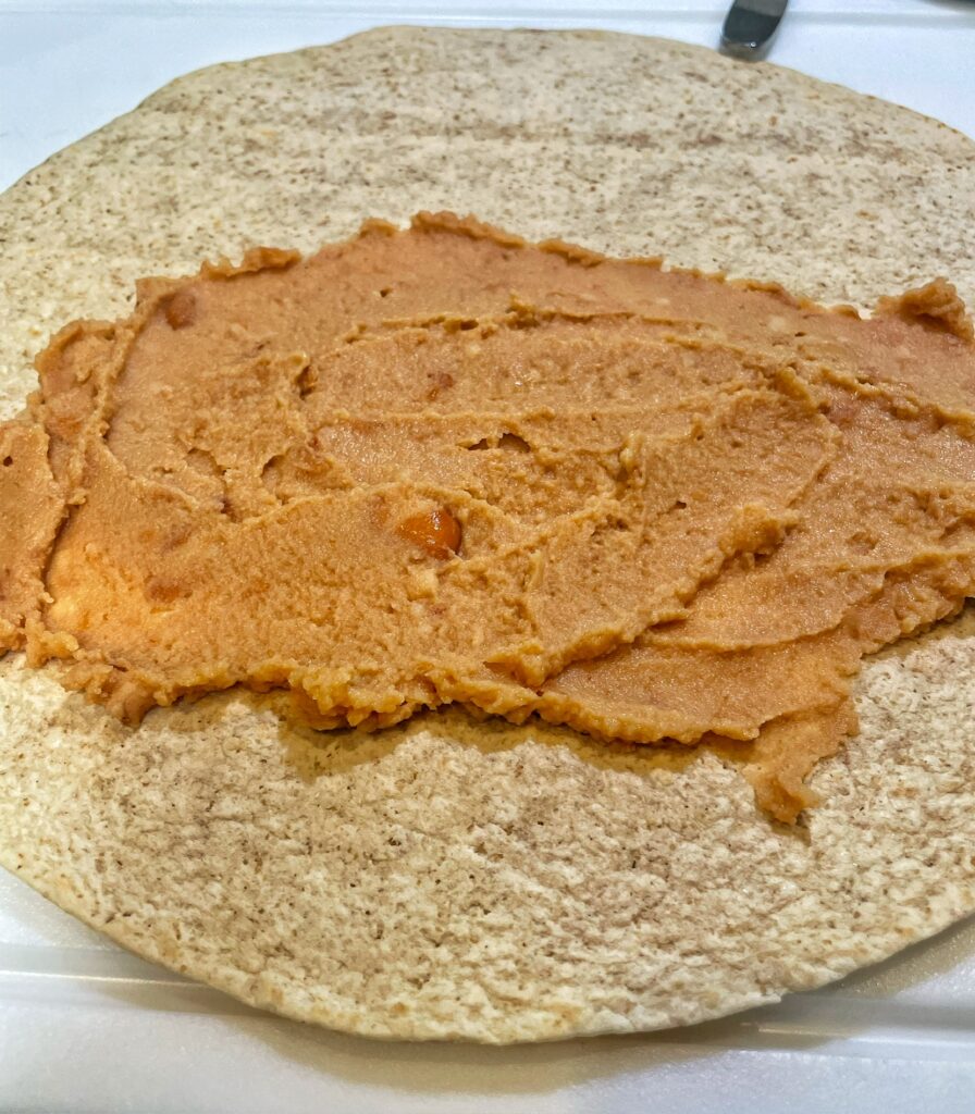 Spreading Refried Beans to Breakfast Burrito